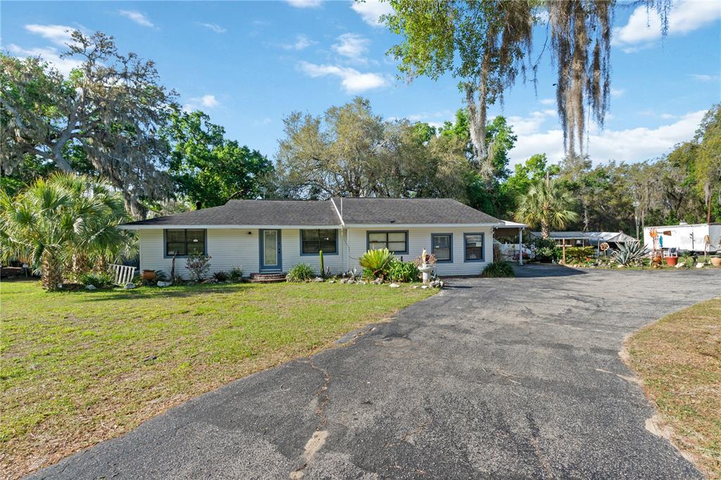 A single-story house with light siding and a dark roof sits behind a paved driveway — 270 W MCCLENDON STREET, LADY LAKE, FL