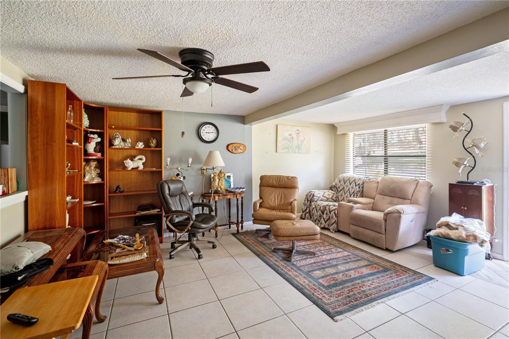 A living room features tile flooring, a ceiling fan, built-in shelving, and various seating options — 270 W MCCLENDON STREET, LADY LAKE, FL
