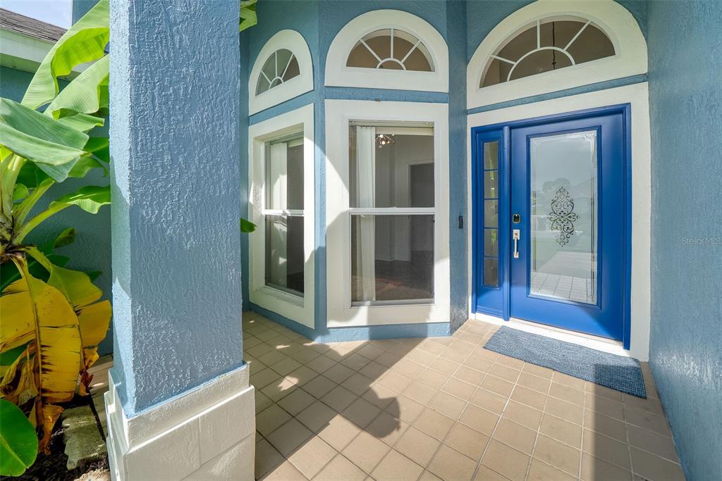 A blue front door with a glass insert sits beside a bay window on a porch — 630 RIOMAR AVENUE, ORLANDO, FL