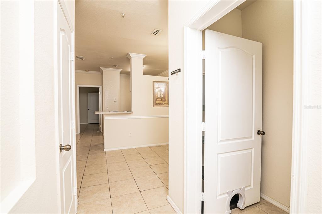 A hallway with tiled floors leads to an open kitchen area with a breakfast bar — 3391 S KIRKMAN ROAD UNIT 1216, ORLANDO, FL