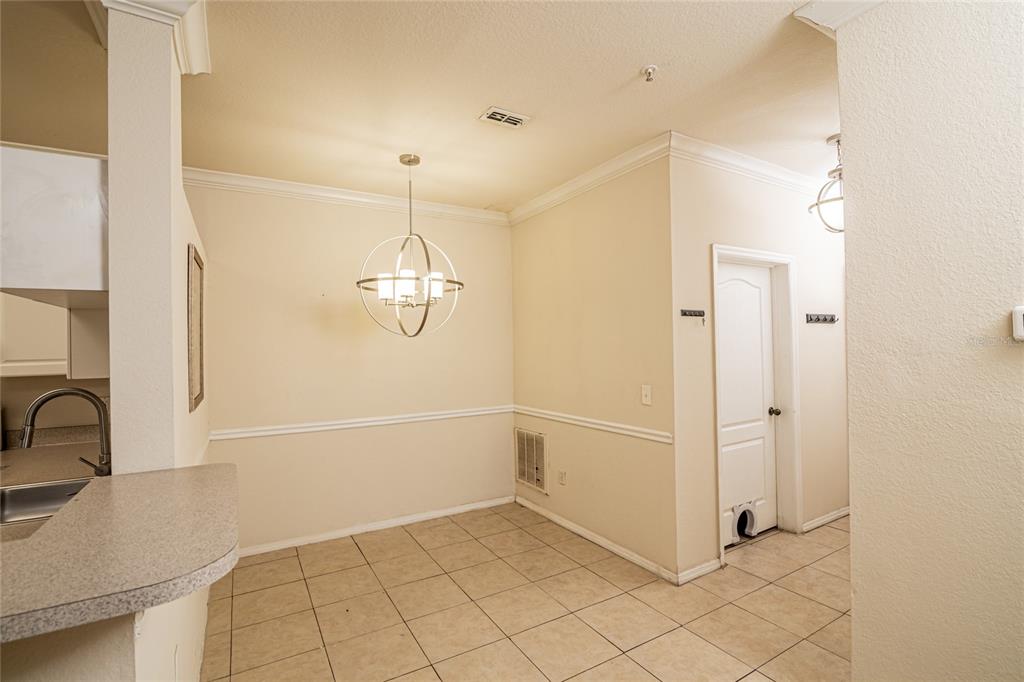 A dining area with tile flooring, a spherical chandelier, and a white door with a pet door — 3391 S KIRKMAN ROAD UNIT 1216, ORLANDO, FL