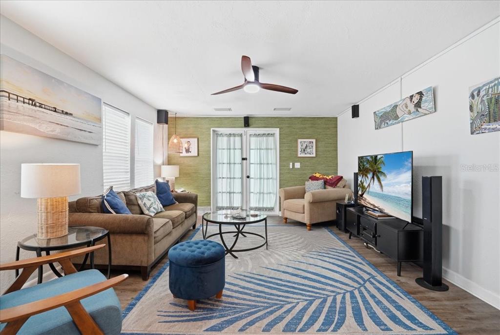 A living room features a brown sofa, a beige armchair, and a large palm-patterned rug — 130 86TH TERRACE, TREASURE ISLAND, FL