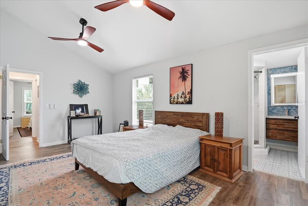 A bedroom features a wooden bed frame, two ceiling fans, and an attached bathroom — 130 86TH TERRACE, TREASURE ISLAND, FL