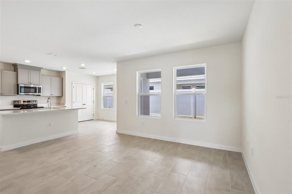 An open-concept kitchen and living area featuring light tile flooring and neutral walls — 2688 MEADOW CREST DRIVE, ST CLOUD, FL