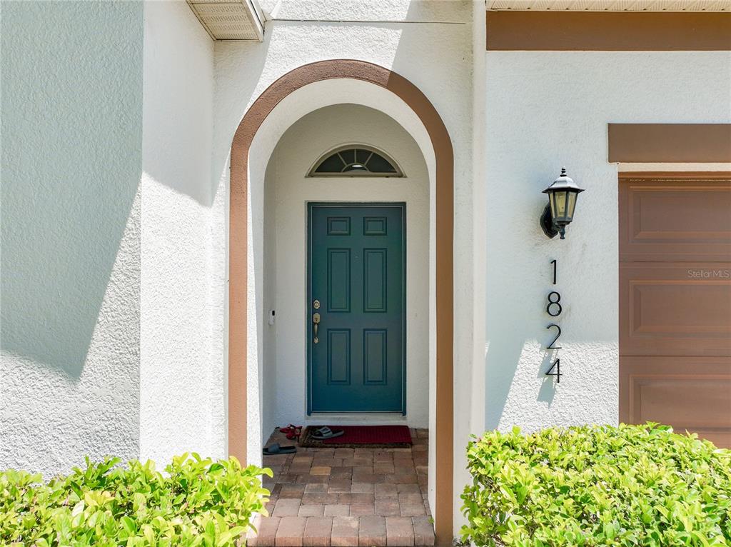 The exterior of a home features a teal front door under an arched entryway — 1824 ARDEN OAKS DRIVE, OCOEE, FL
