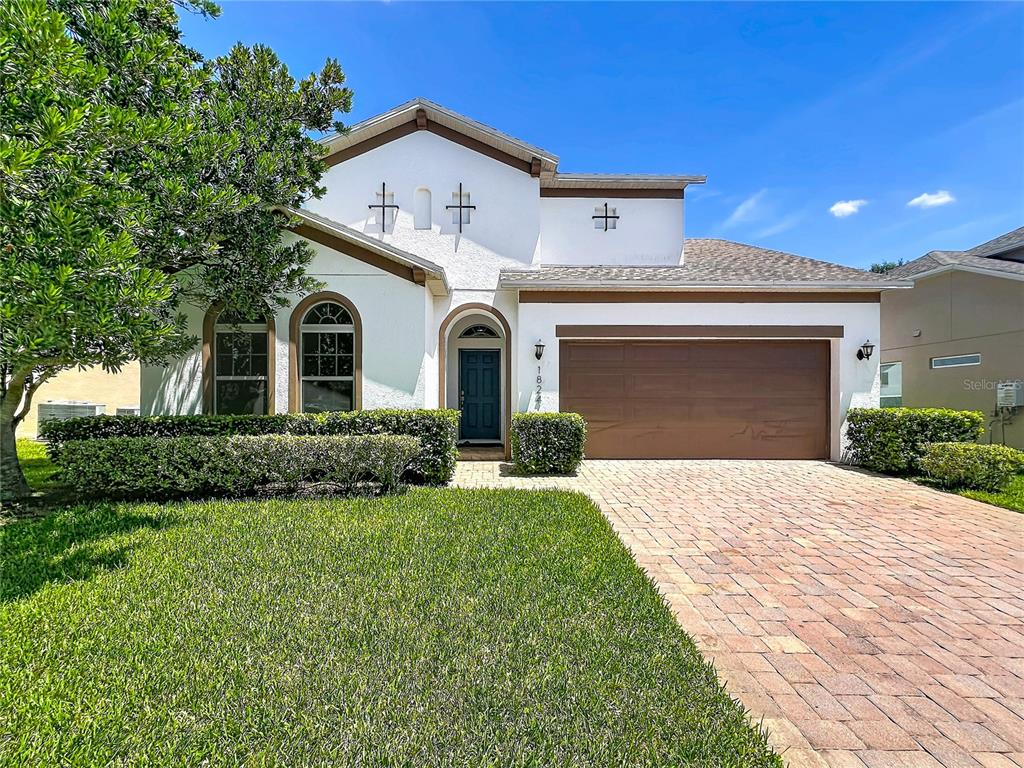 A single-story house with a white stucco exterior, brown garage door, and a brick driveway — 1824 ARDEN OAKS DRIVE, OCOEE, FL