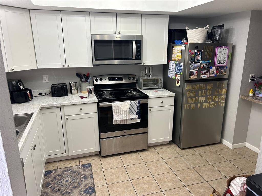 A kitchen features white cabinets, stainless steel appliances, and a refrigerator decorated with magnets — 6301 58TH STREET N UNIT 501, PINELLAS PARK, FL