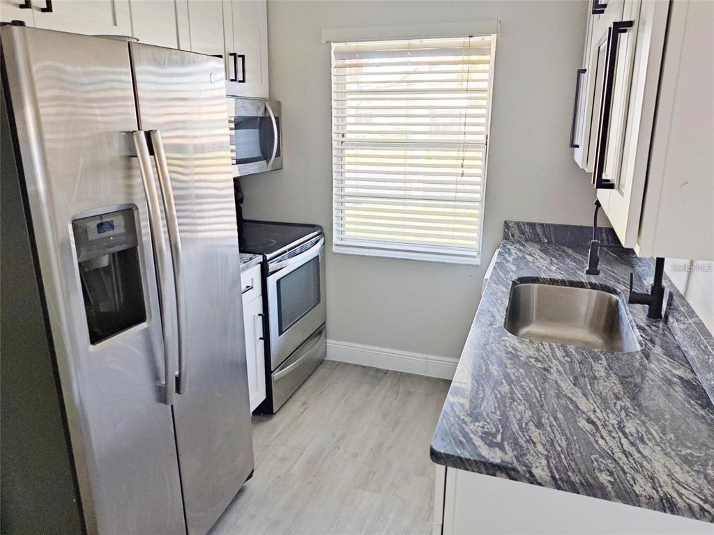 A kitchen features stainless steel appliances, white cabinets, and dark granite countertops — 2472 ENTERPRISE ROAD UNIT 6, CLEARWATER, FL