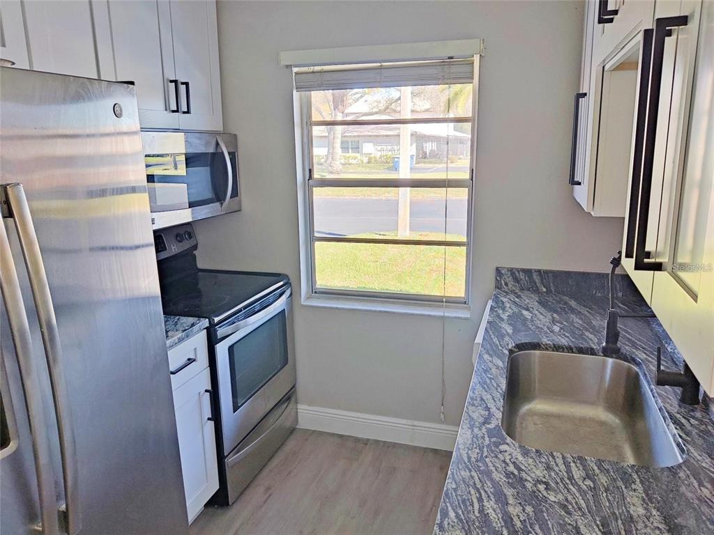 A kitchen features stainless steel appliances, white cabinets, and blue-veined granite countertops — 2472 ENTERPRISE ROAD UNIT 6, CLEARWATER, FL