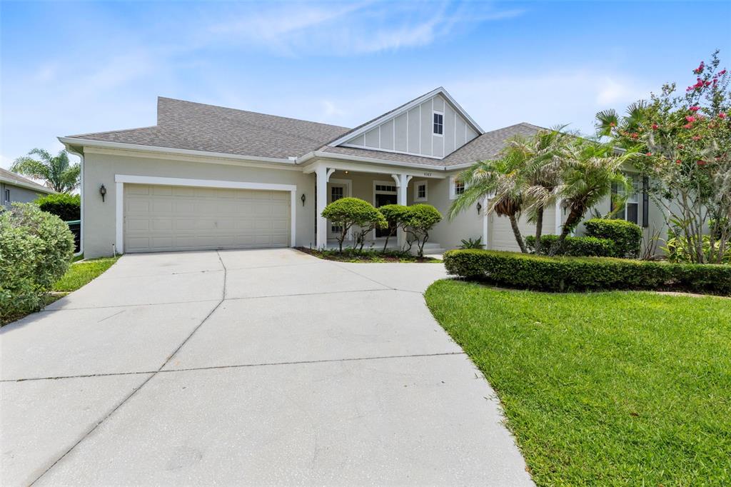 A single-story house with a beige exterior, a two-car garage, and a landscaped front yard — 6363 SEDONA LEAF COURT, WINDERMERE, FL