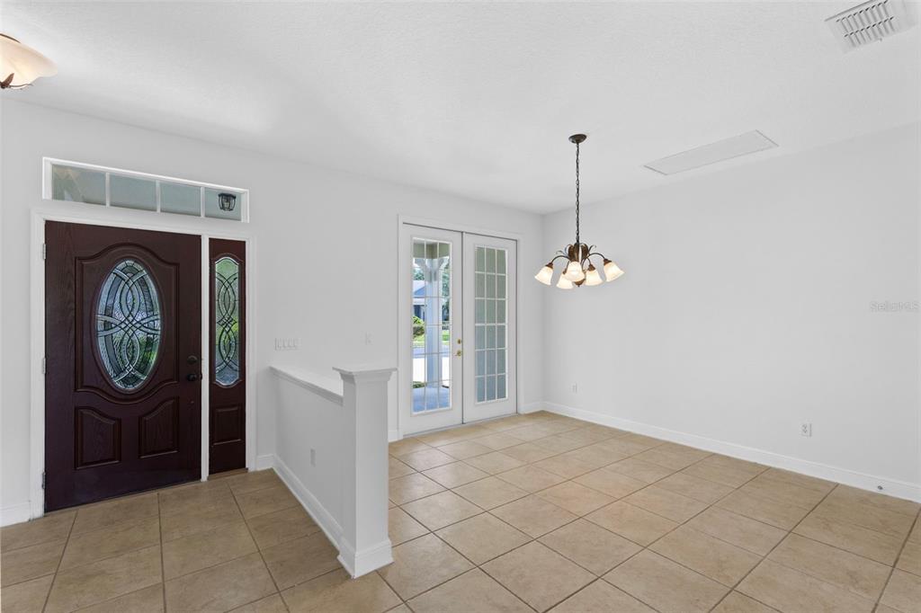 An entryway with tile flooring, a dark wood front door, and a dining area — 6363 SEDONA LEAF COURT, WINDERMERE, FL