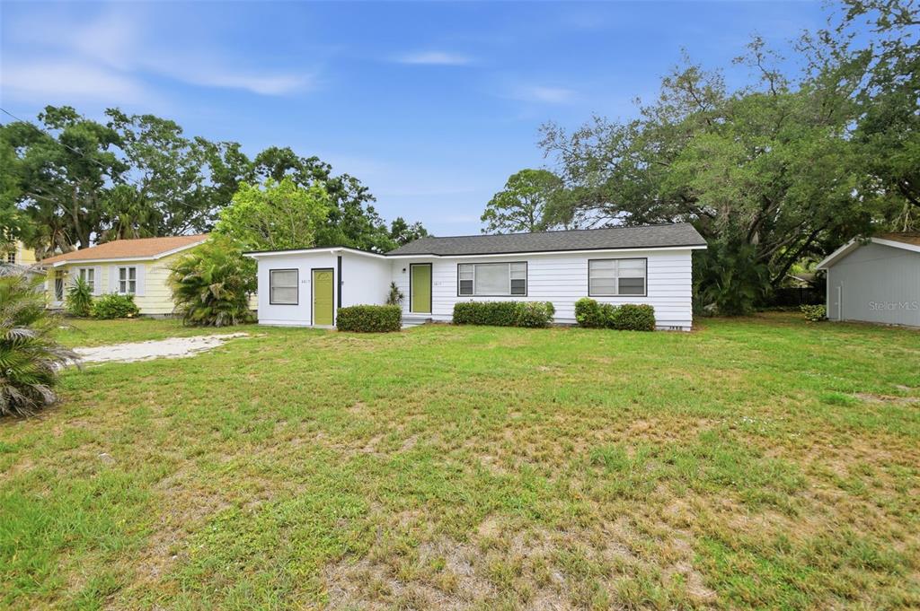 A white, single-story house with a green door and a large front lawn — 2817 HAWTHORNE STREET, SARASOTA, FL