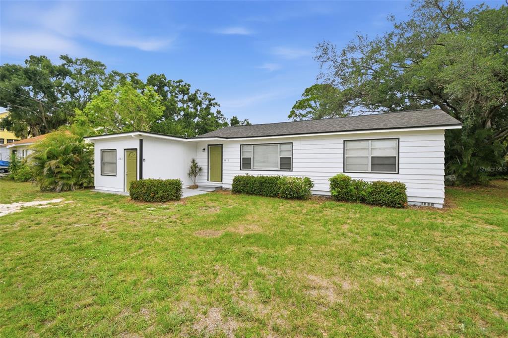 A single-story house with white horizontal siding, a dark roof, and two green doors — 2817 HAWTHORNE STREET, SARASOTA, FL
