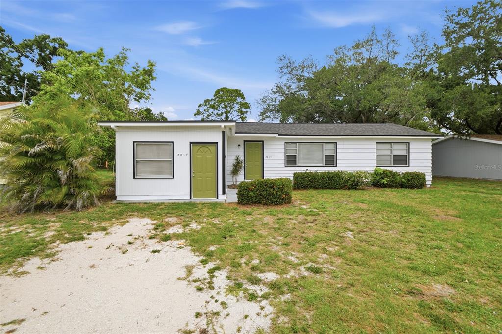 A single-story white house with two green doors and a gravel driveway — 2817 HAWTHORNE STREET, SARASOTA, FL