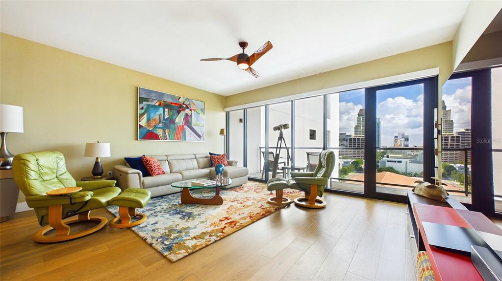 A living room features light wood floors, a beige sofa, two green armchairs, and floor-to-ceiling windows — 199 DALI BOULEVARD UNIT 1106, ST PETERSBURG, FL