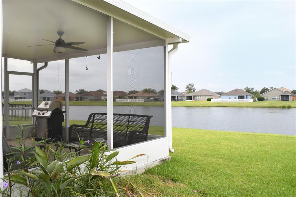 A screened-in patio features a grill, outdoor furniture, and a view of a lake — 11223 82ND STREET E, PARRISH, FL