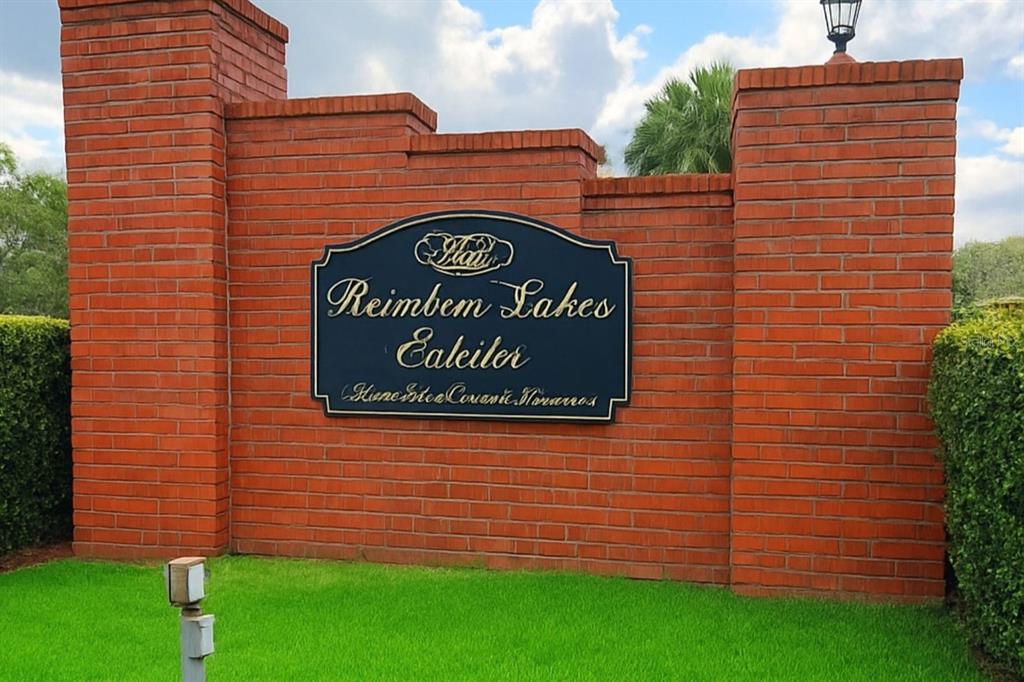 A brick wall features a sign for Reimbem Lakes Ealeiler surrounded by green hedges — 0 RAINBOW LAKES BOULEVARD, DUNNELLON, FL
