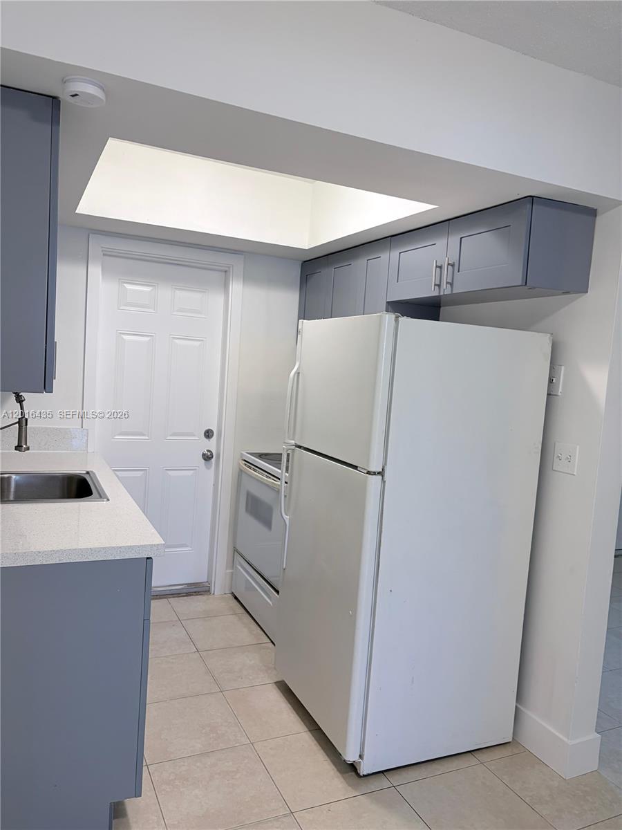 A kitchen features gray cabinets, white appliances, a light countertop, and a white door — 31 NW 163rd St # 65, Miami FL 33169, MIAMI, FL