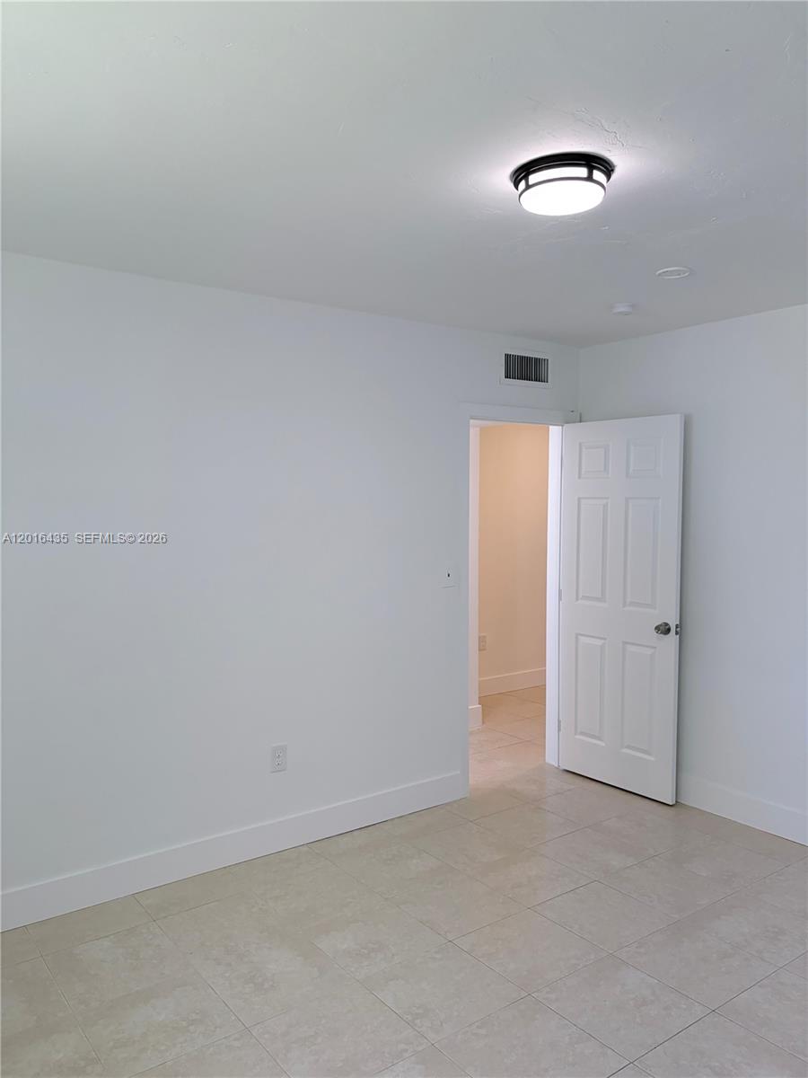 A room with white walls, tile flooring, a ceiling light, and an open doorway — 31 NW 163rd St # 65, Miami FL 33169, MIAMI, FL