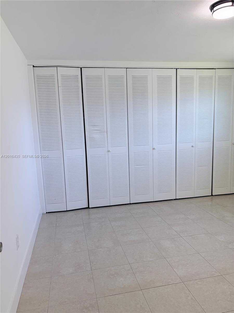A room features white louvered closet doors and light-colored tile flooring — 31 NW 163rd St # 65, Miami FL 33169, MIAMI, FL