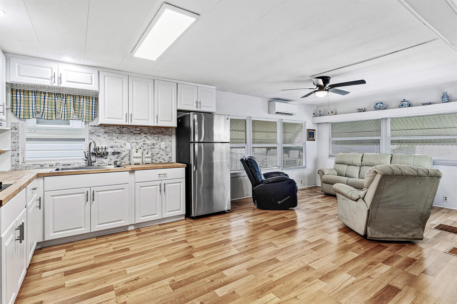 A kitchen and living area with white cabinets, stainless steel appliances, and wood-look flooring — 202 Palm Drive # I, Briny Breezes FL 33435, BRINY BREEZES, FL