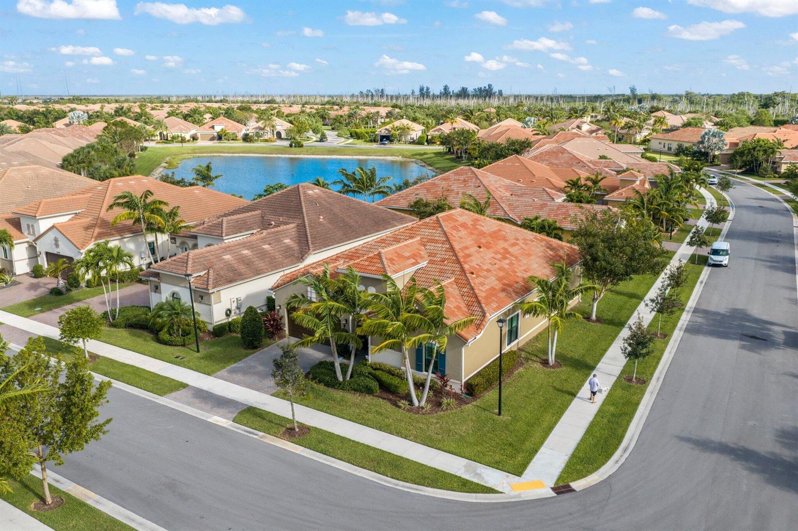 An aerial view of a suburban neighborhood featuring houses with tiled roofs and a lake — 11759 Palermo Road, Parkland FL 33076, PARKLAND, FL