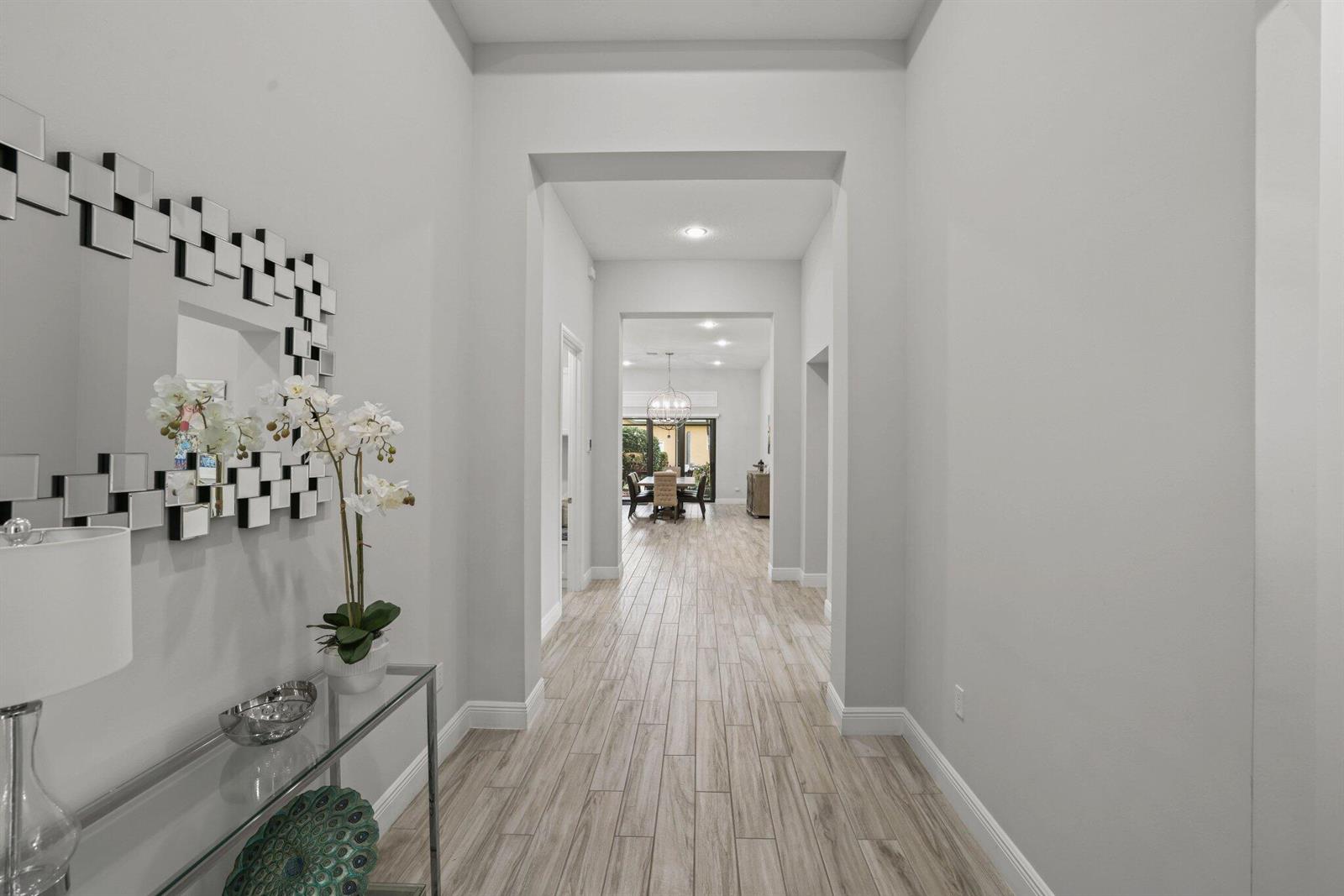 A bright hallway with light wood-look tile flooring leads toward a dining area — 11759 Palermo Road, Parkland FL 33076, PARKLAND, FL