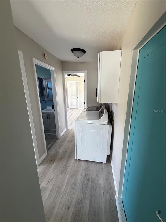 A laundry area with a white washer and dryer, wood-look flooring, and a teal door — 3125 BAYBERRY AVENUE, PUNTA GORDA, FL