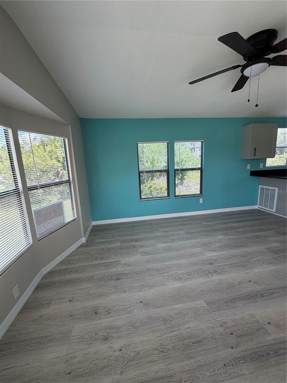 An empty room features teal walls, light wood-look flooring, and a ceiling fan — 3125 BAYBERRY AVENUE, PUNTA GORDA, FL