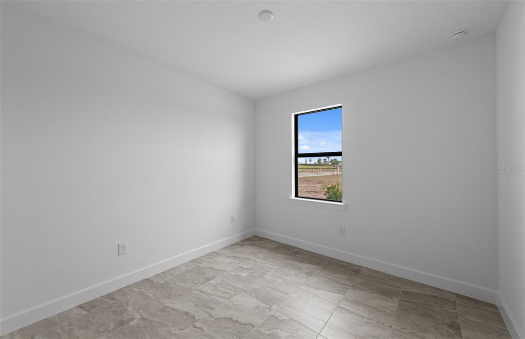 An empty room with white walls, tiled flooring, and a single window overlooking a field — 18937 INDIAN ROCK PLACE, LAKEWOOD RANCH, FL
