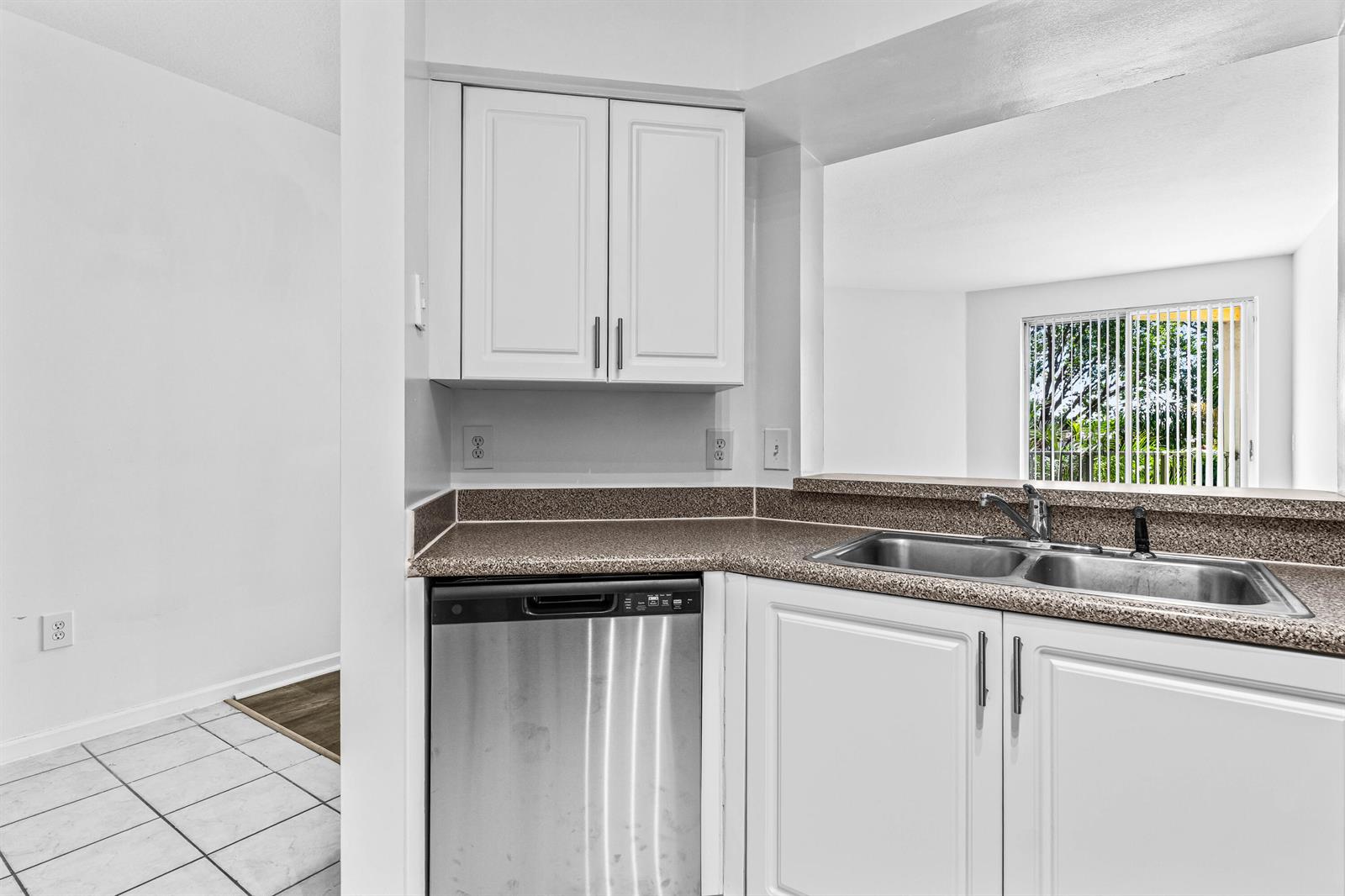 A kitchen features white cabinets, a stainless steel dishwasher, and a double-basin sink with countertops — 1951 Brandywine Road E # 105, West Palm Beach FL 33409, WEST PALM BEACH, FL