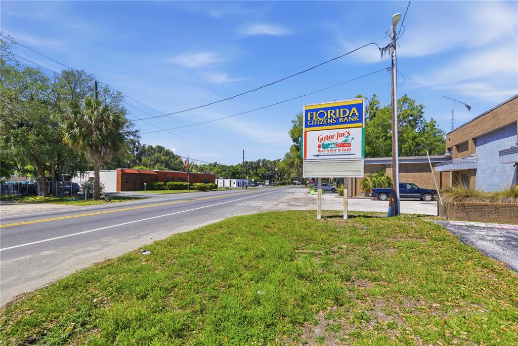 A roadside sign for Florida Citizens Bank and Gator Joe's stands beside a paved road — 12300 SE 135TH AVENUE, OCKLAWAHA, FL