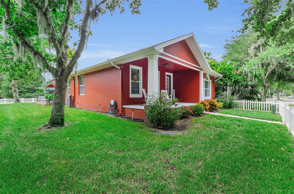 A red house with a front porch and white trim sits on a grassy lawn — 3237 TOWN AVENUE, NEW PORT RICHEY, FL