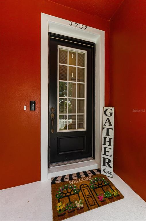 A black front door with a glass pane sits between bright red walls — 3237 TOWN AVENUE, NEW PORT RICHEY, FL