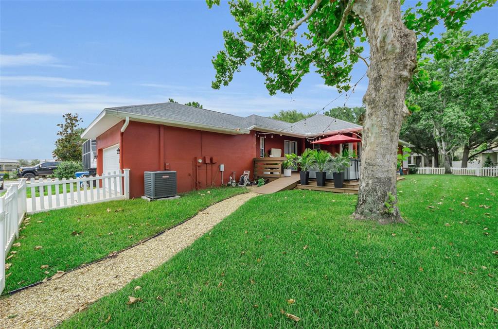 A red house with a gravel path, a wooden deck, and a large tree in front — 3237 TOWN AVENUE, NEW PORT RICHEY, FL