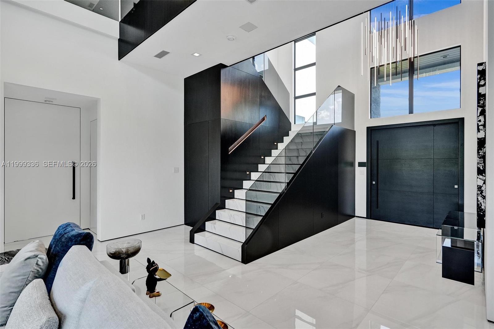 A modern foyer features a marble staircase with glass railings and black wood paneling — 17811 SW 58th St, Southwest Ranches FL 33331, SOUTHWEST RANCHES, FL