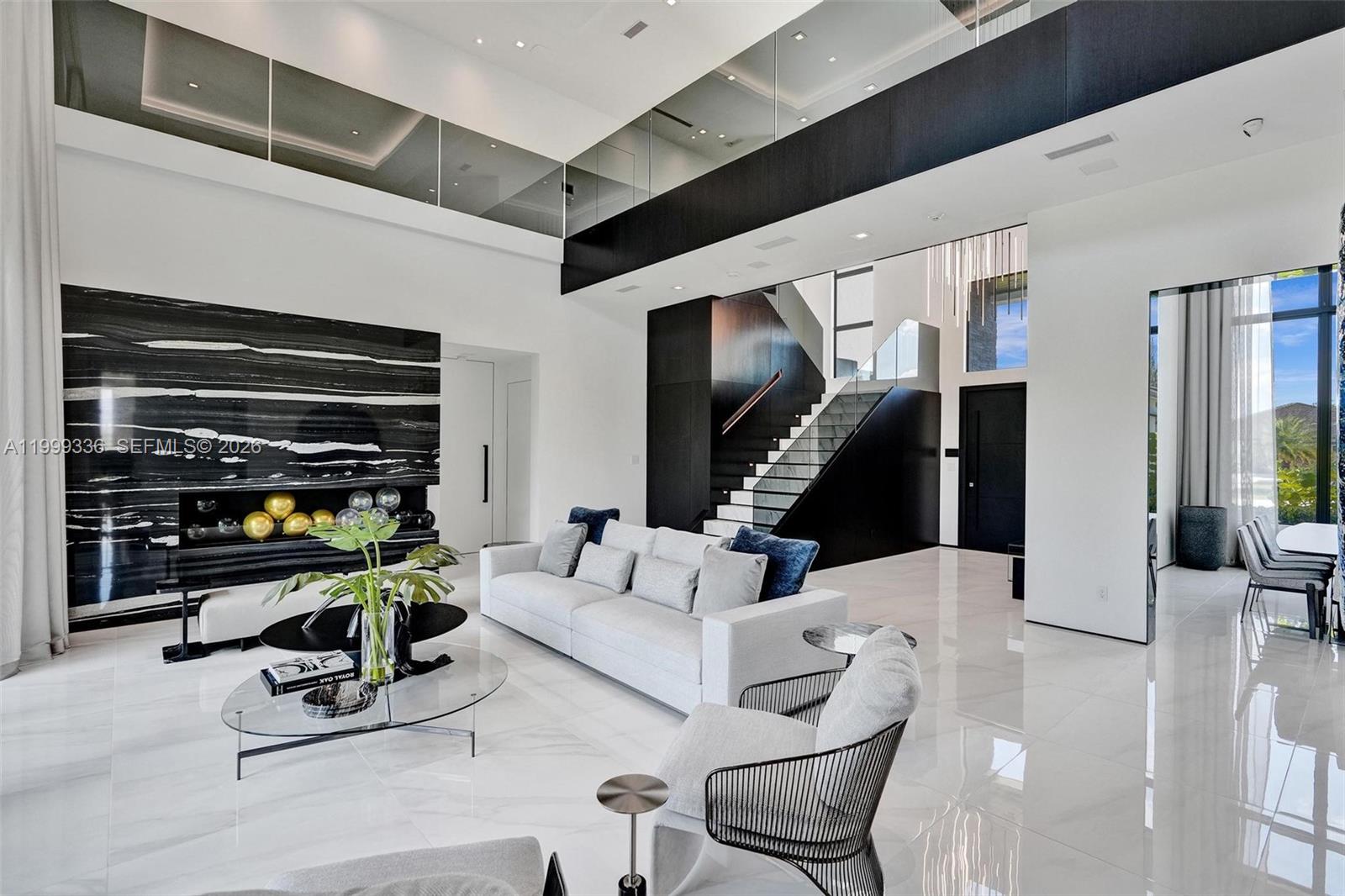 A modern living room features high ceilings, a black marble fireplace, and a glass staircase — 17811 SW 58th St, Southwest Ranches FL 33331, SOUTHWEST RANCHES, FL