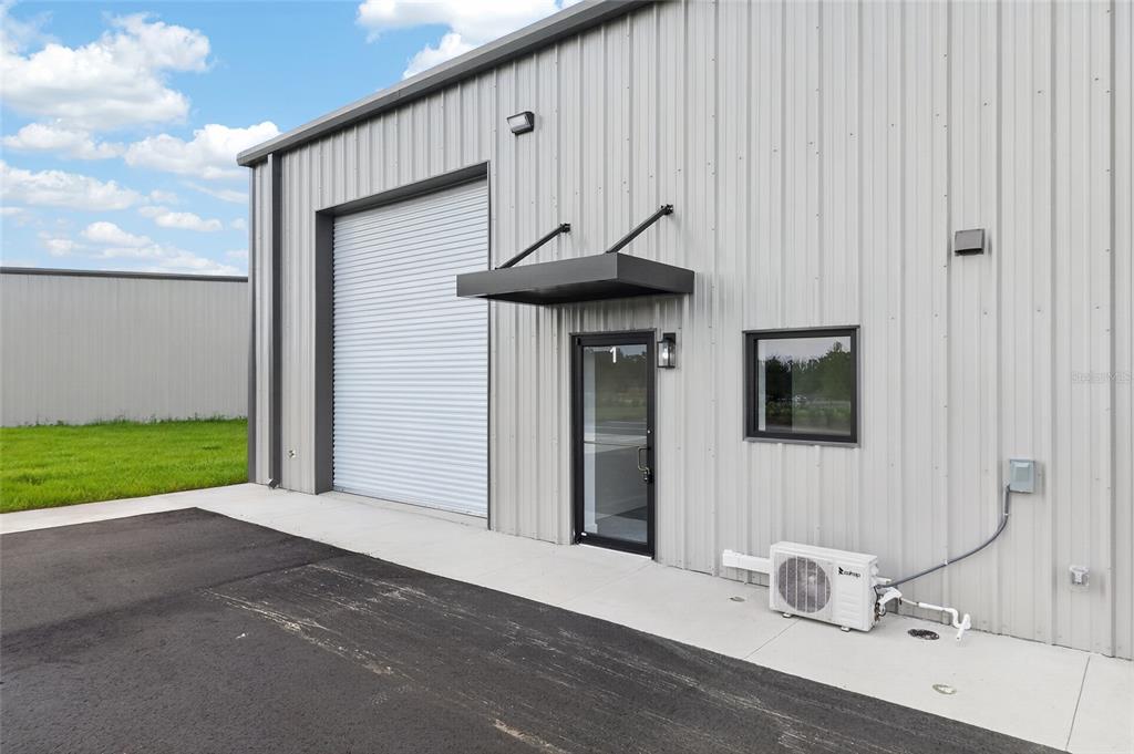 An exterior view of a metal warehouse building featuring a roll-up door and entrance — 5425 SE 133 PLACE, BELLEVIEW, FL