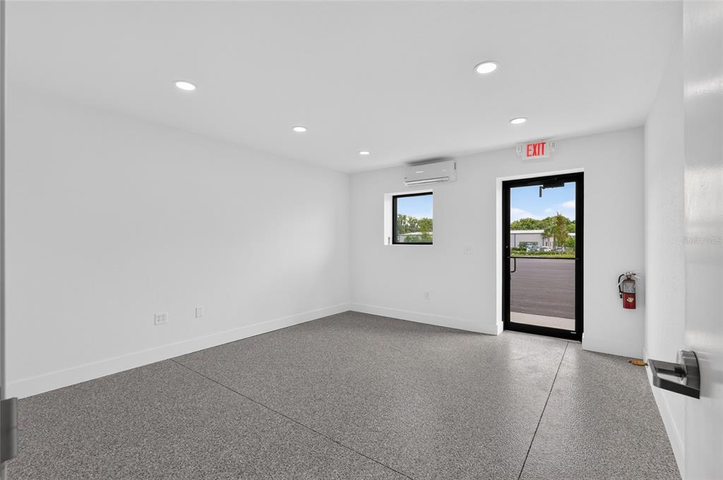 A minimalist room with white walls, recessed lighting, a gray speckled floor, and an exit — 5425 SE 133 PLACE, BELLEVIEW, FL