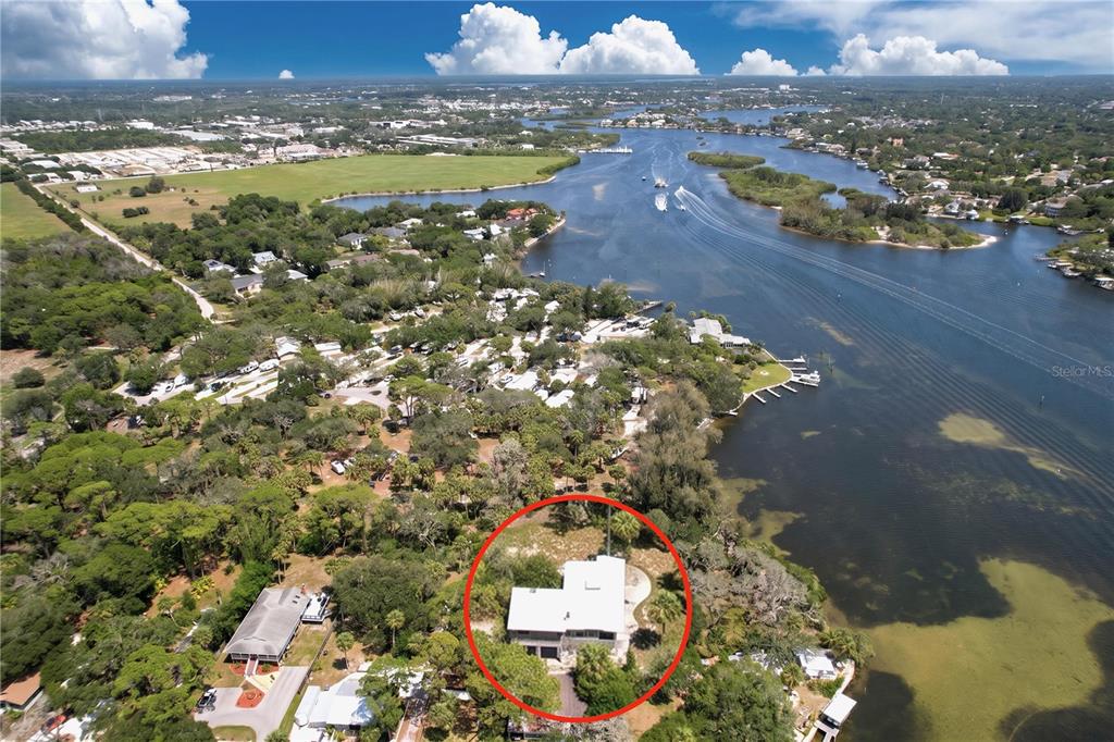 An aerial view shows a house with a white roof surrounded by trees near water — 1275 MICKLER LANE, TARPON SPRINGS, FL