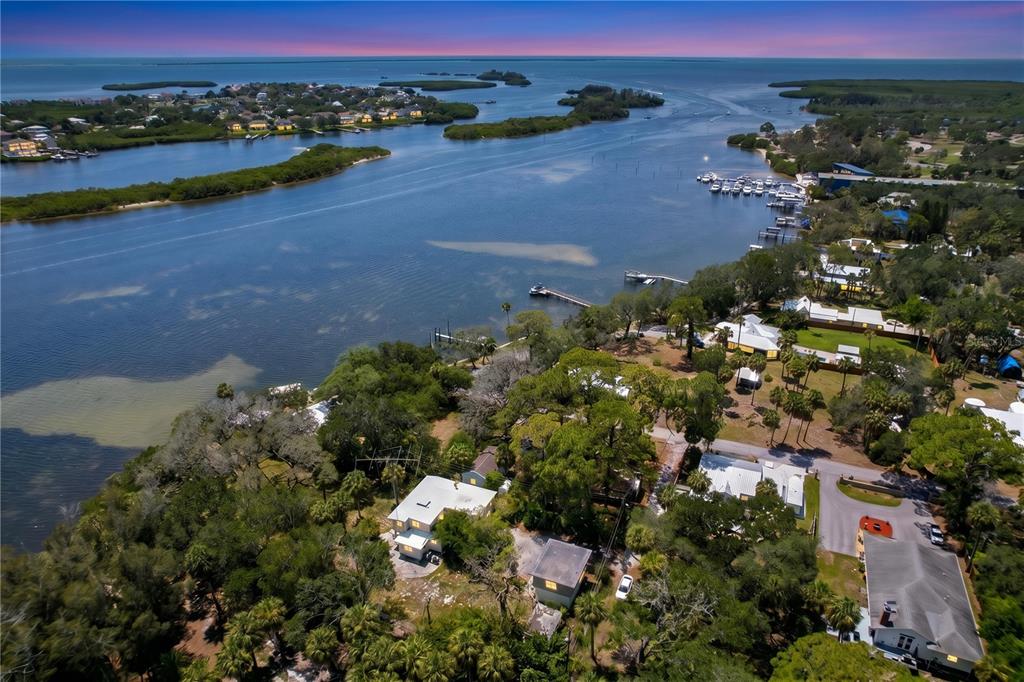 An aerial view shows waterfront homes surrounded by trees near a bay with boat docks — 1275 MICKLER LANE, TARPON SPRINGS, FL