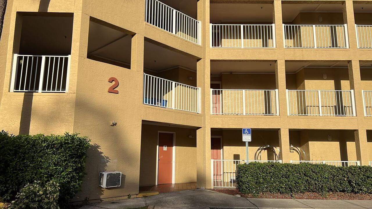 A multi-story apartment building exterior featuring tan stucco walls, white railings, and a numbered unit — 6337 Parc Corniche Dr Drive # 2111, Orlando FL 32821, ORLANDO, FL