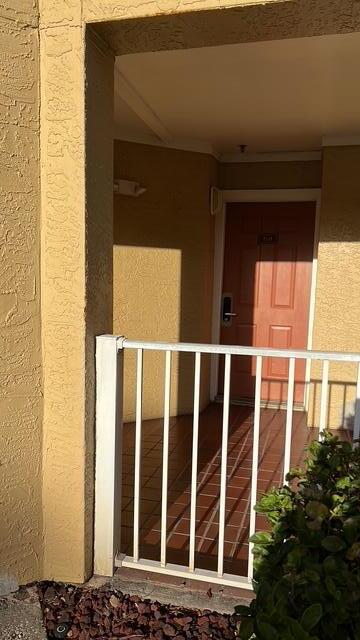 A view of a covered apartment entryway with a white railing and a red door — 6337 Parc Corniche Dr Drive # 2111, Orlando FL 32821, ORLANDO, FL