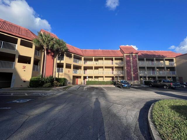 A multi-story apartment building with a red roof and palm trees in a parking lot — 6337 Parc Corniche Dr Drive # 2111, Orlando FL 32821, ORLANDO, FL