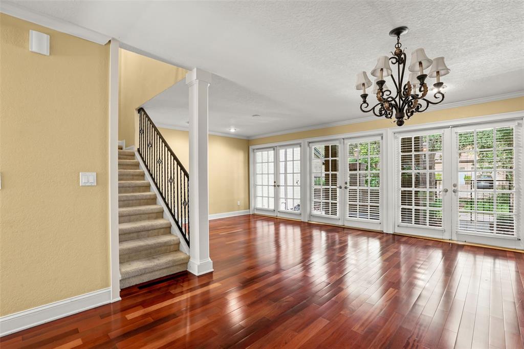 A room with hardwood floors, a staircase with iron railings, and several glass-paned doors — 1134 WASHINGTON AVENUE UNIT 13C, WINTER PARK, FL