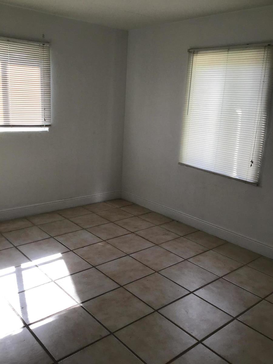 An empty room with white walls, beige tile flooring, and two windows with blinds — 364 Johnston Street, Fort Pierce FL 34982, FORT PIERCE, FL