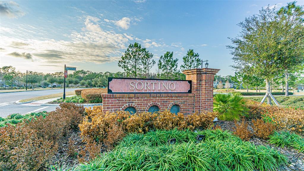 A brick monument sign with the name Sortino stands in a landscaped neighborhood entrance — 5062 SAN MARTINO DRIVE, WESLEY CHAPEL, FL