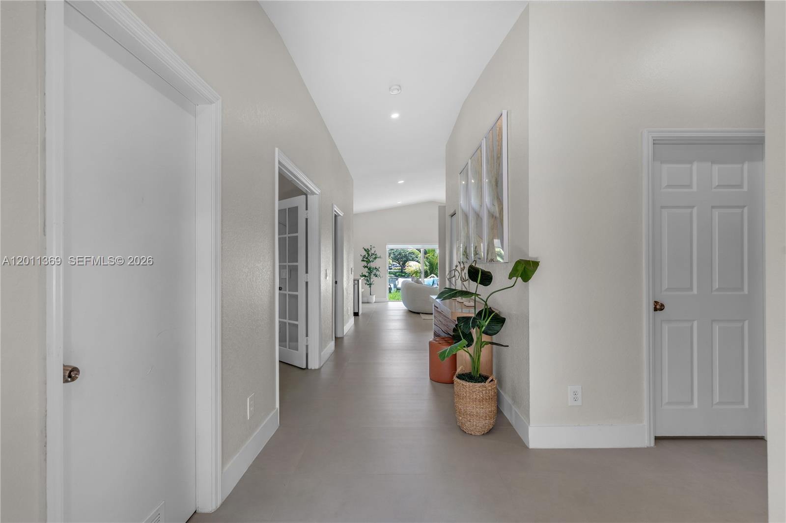 A hallway with light-colored walls and tile flooring leads toward a bright living area — 2001 SW 104th Ave, Miramar FL 33025, MIRAMAR, FL
