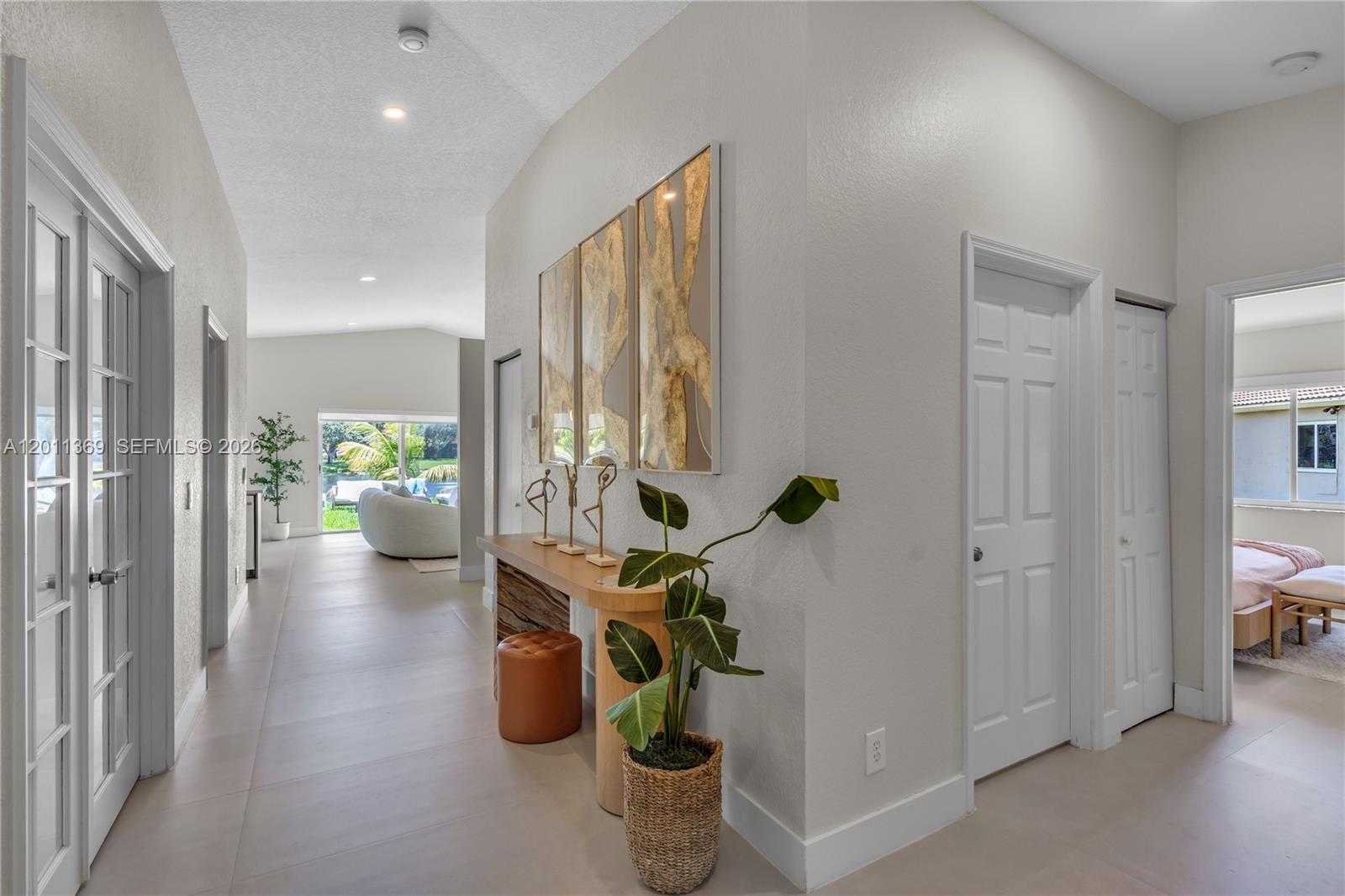 A hallway with light tile flooring leads toward a living area with a view outside — 2001 SW 104th Ave, Miramar FL 33025, MIRAMAR, FL