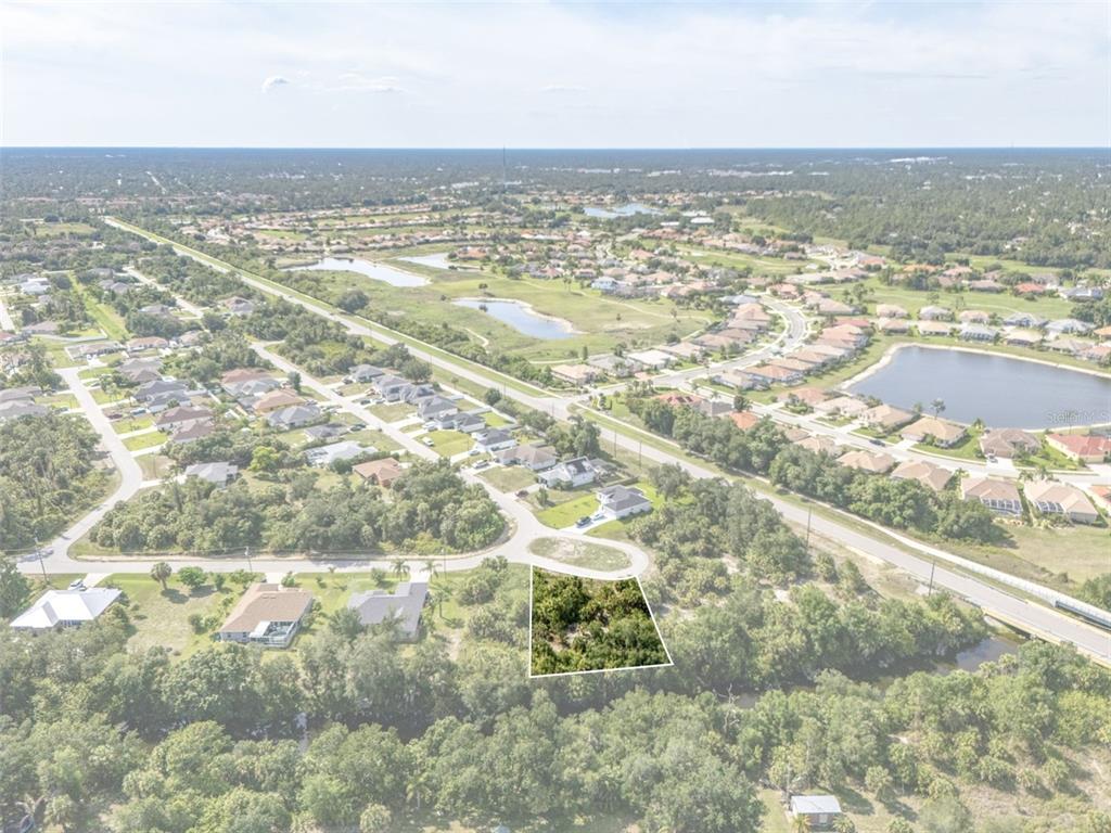 An aerial view shows a vacant, wooded residential lot outlined in white within a neighborhood — Lot 15 ROANOKE ROAD, NORTH PORT, FL